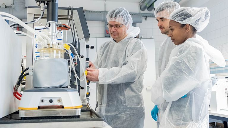 Personen in Reinraumkleidung, Haarschutz, Handschuhe im Labor
