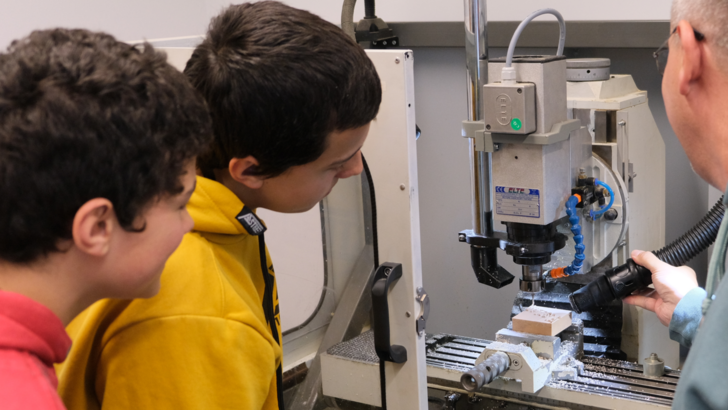 Personen schauen in eine CNC-Drehmaschine