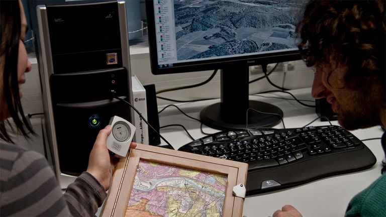 Person mit Kompass und Karte am PC in einem Büro